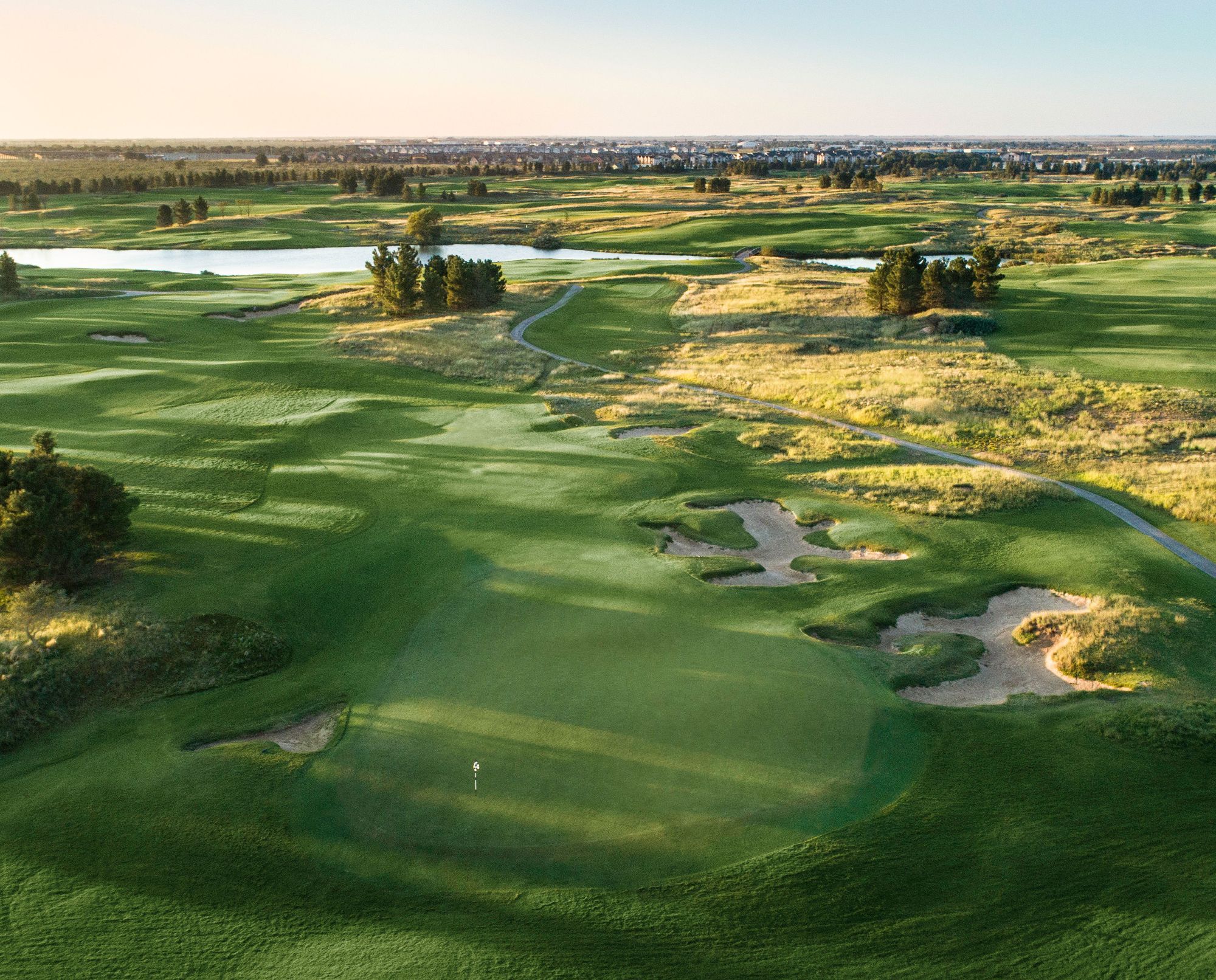 A view of a golf hole with sand dunes to the right.